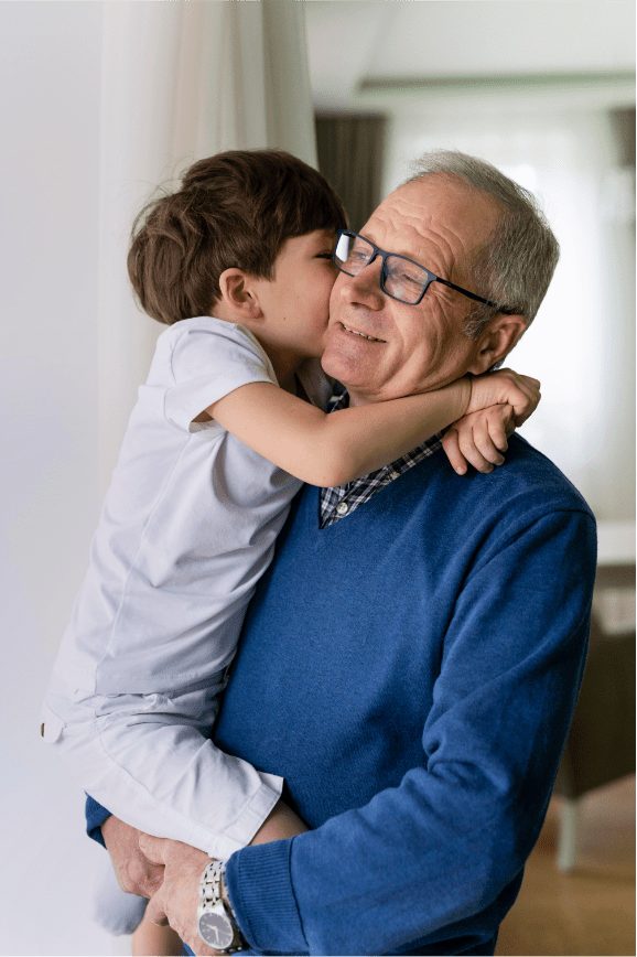 A grandfather holding his grandchild by a window